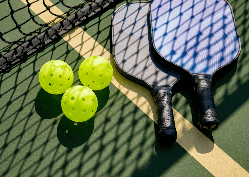 A table tennis racket and three balls on the ground.