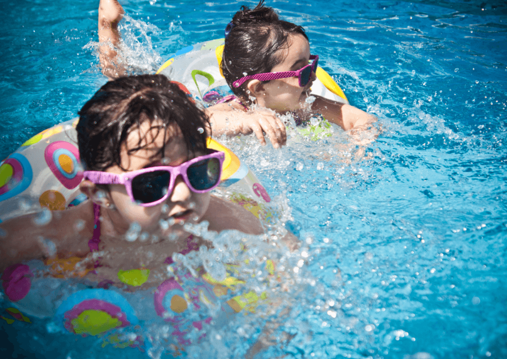 Two children swimming in a pool with floats.